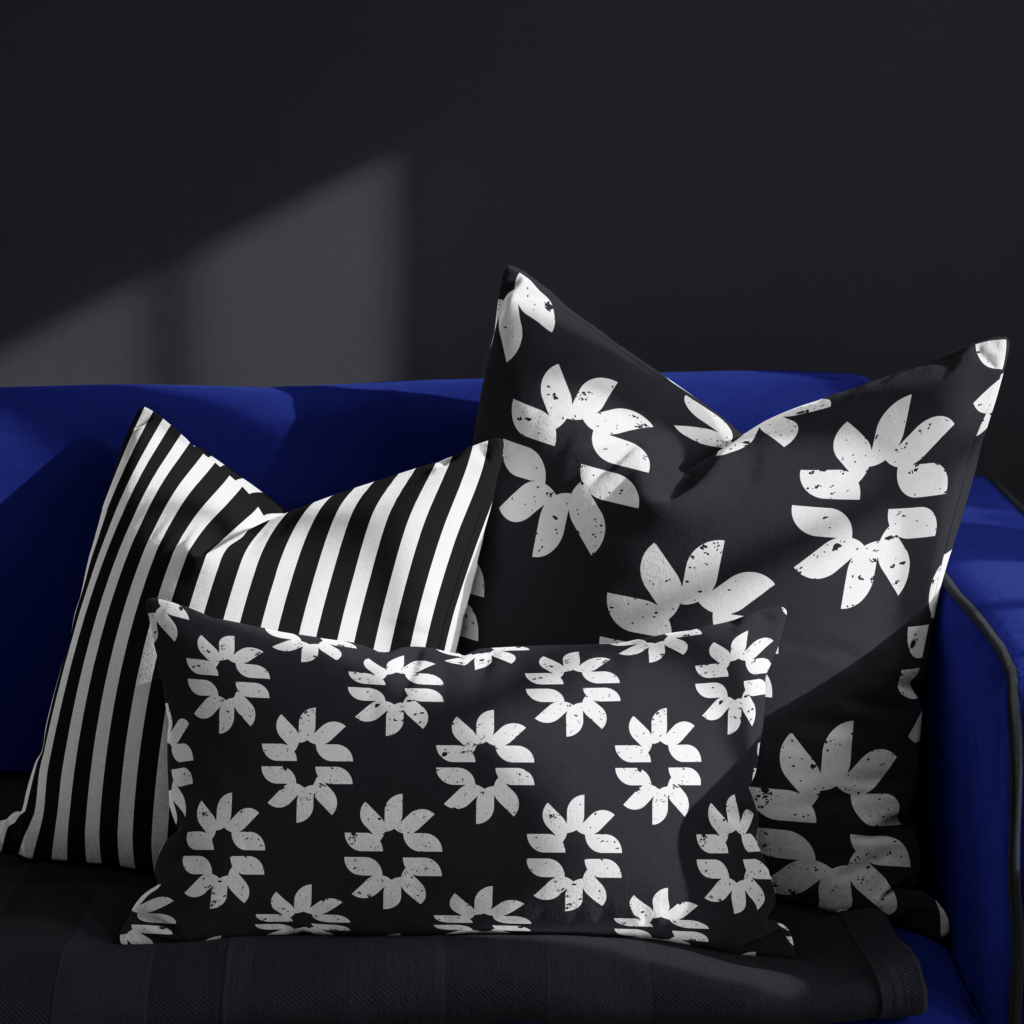Black and white modern floral and striped throw pillow collection styled on a dark couch.